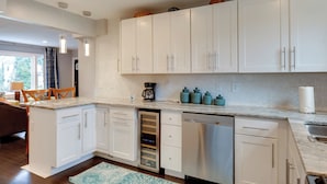 A modern kitchen with white cabinets, a built-in dishwasher, and a coffee maker. - Charming Baltimore Getaway - 5 Miles to Downtown! (Baltimore)