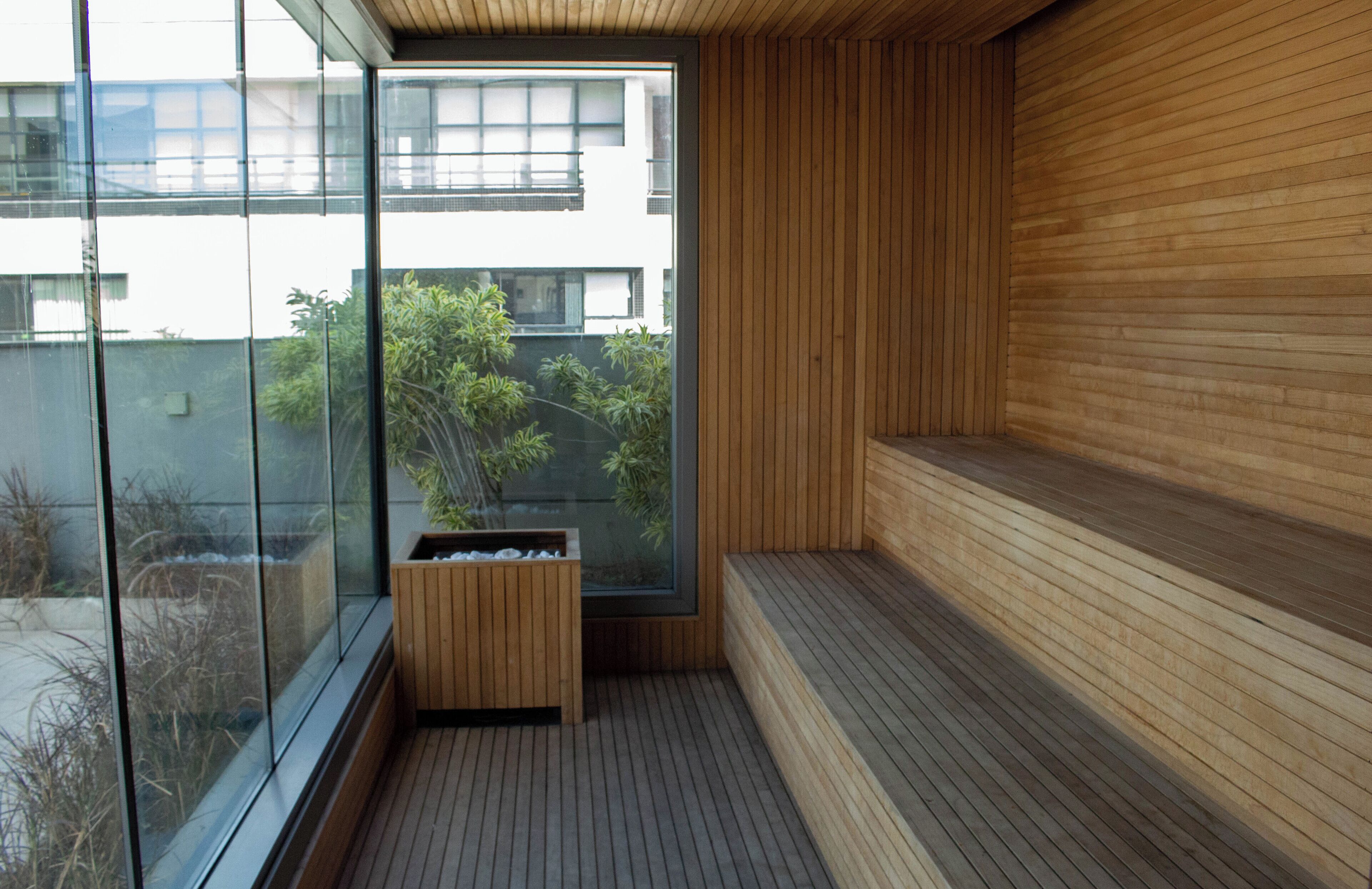 A modern interior with a wooden bench and a glass partition.