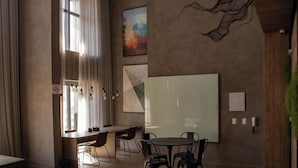 A modern conference room with a large whiteboard, a round table with chairs, and a view of the city through large windows. - Belint Paulista (São Paulo)