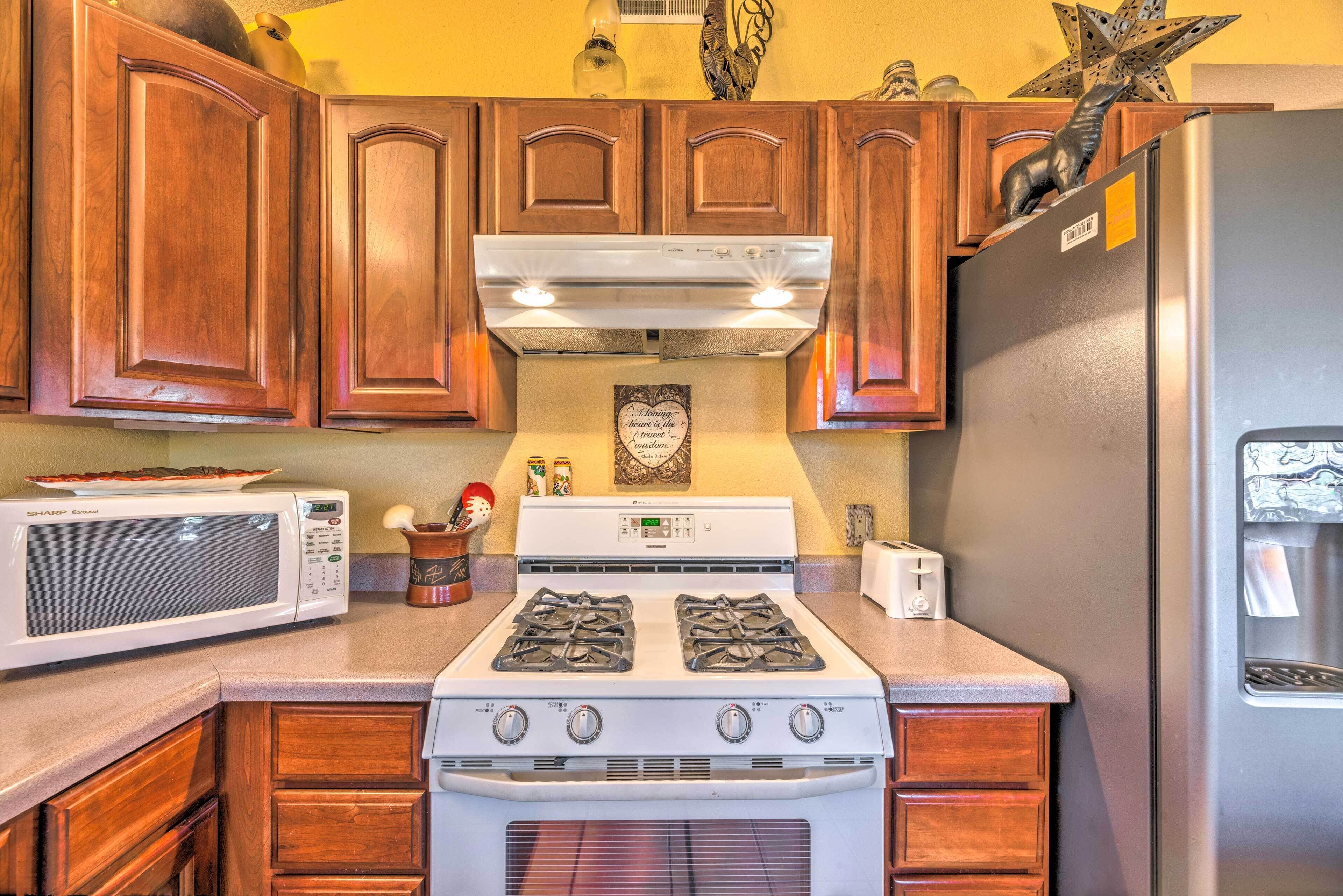 A kitchen with wooden cabinets, a microwave, a stove, and a refrigerator.