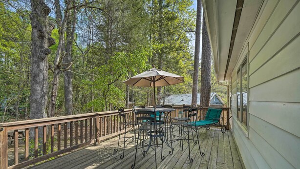 Eine Holzterrasse mit Gartenmöbeln, darunter ein Tisch und Stühle, sowie ein großer Sonnenschirm.
