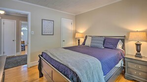 Ein Schlafzimmer mit Bett, Nachttischen, einer Tür und einer Wand mit einem gerahmten Zitat.