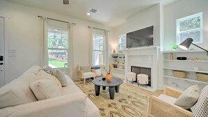 A modern living room with a white sofa, a round coffee table, and a fireplace. There is a television mounted above the fireplace and a ceiling fan. - Canyon Lake Home w/ Deck ~ 1 Mi to Comal Park (Canyon Lake)