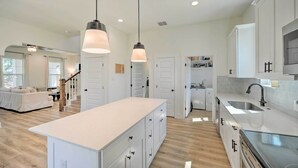 A modern kitchen with white cabinets, a large island, and pendant lighting. - Canyon Lake Home w/ Deck ~ 1 Mi to Comal Park (Canyon Lake)
