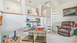A living room with a chessboard, a brown leather armchair, and a staircase. - Bayfront Niceville Getaway w/ Private Dock! (Niceville)