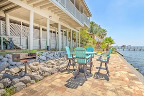 A covered outdoor patio with stone walls, a pool, and a view of the water.