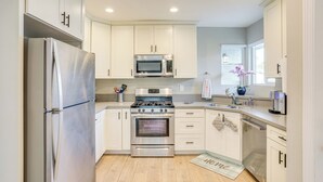 A modern kitchen with white cabinets, stainless steel appliances, and a wooden floor. - Fullerton Vacation Rental w/ Private Pool! (Fullerton)