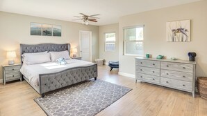 A bedroom with a tufted bed, bedside lamps, a dresser, and artwork on the walls. - Fullerton Vacation Rental w/ Private Pool! (Fullerton)