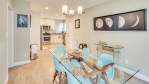 A modern kitchen with stainless steel appliances, a glass dining table with blue chairs, and a chandelier. - Fullerton Vacation Rental w/ Private Pool! (Fullerton)