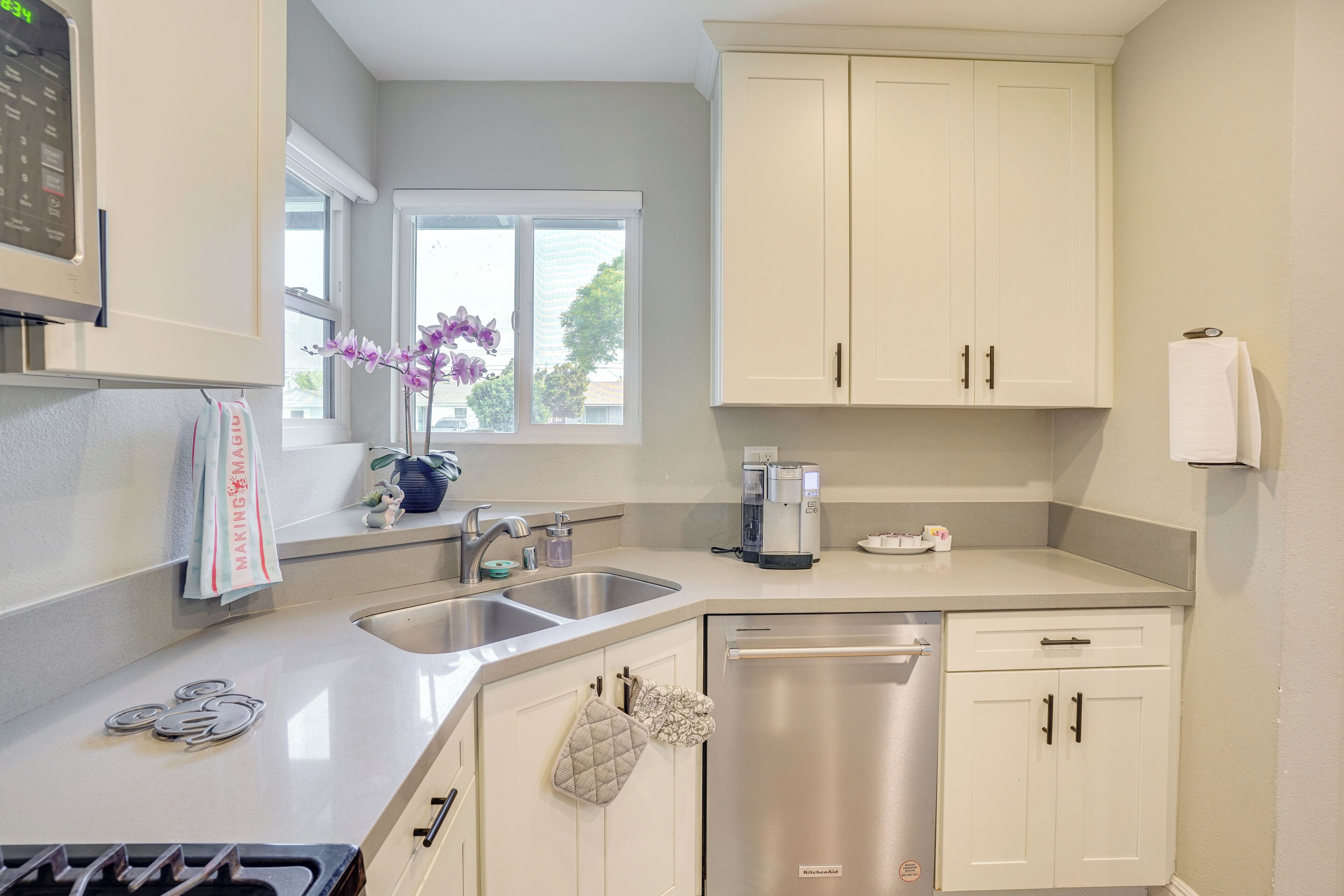 A modern kitchen with a dishwasher, double sink, and a coffee maker.