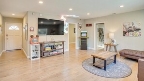 A living room with a flat-screen TV, a coffee table, a sofa, and a gaming console. - Fullerton Vacation Rental w/ Private Pool! (Fullerton)