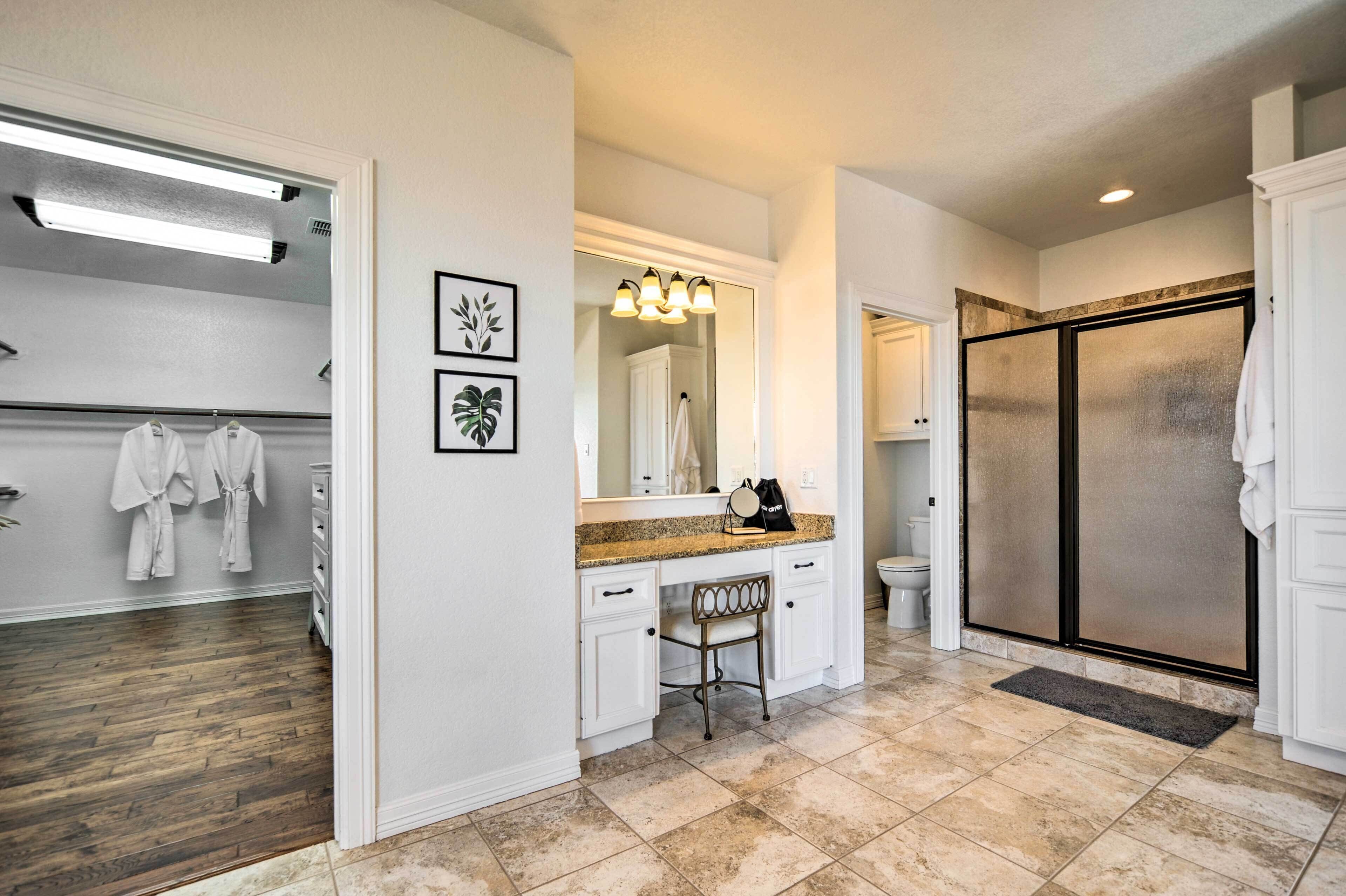 A bathroom with a vanity, a mirror, a towel rack, and a shower area.