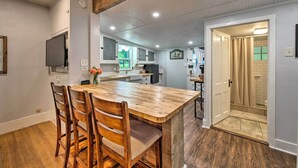 Una cocina con una isla de madera, sillas y una mesa de comedor.