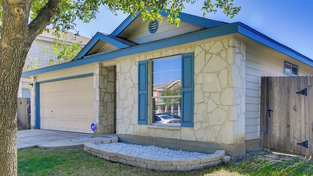 Uma casa com fachada de pedra, uma garagem e cerca de madeira.