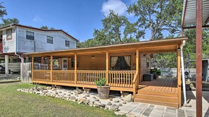 A covered wooden deck with a stone pathway leading to a house.