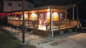 A wooden cabin with a covered porch, stone pathway, and a small garden area.