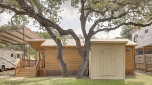 Una casa de madera con porche cubierto y un cobertizo pequeño.