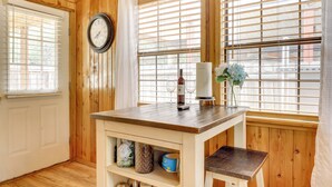 Un interior de madera con una mesa, un reloj y una ventana con persianas.