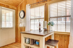 A wooden interior with a wooden table, a clock, and a window with blinds. - Couples Cabin w/ Luxury Deck, 1 Mi to Canyon Lake! (Canyon Lake)