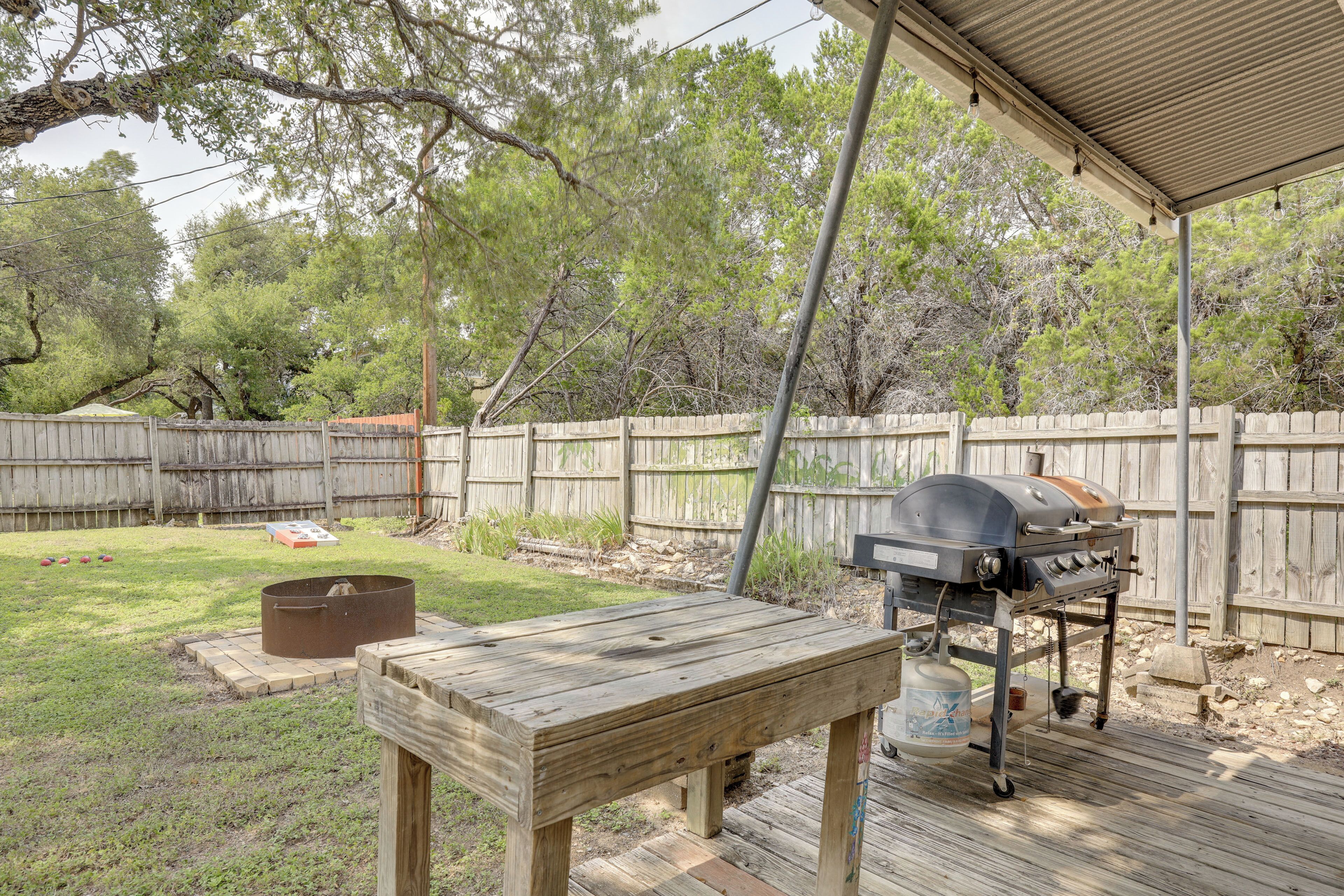 An outdoor patio with a grill, a wooden table, and a fire pit.