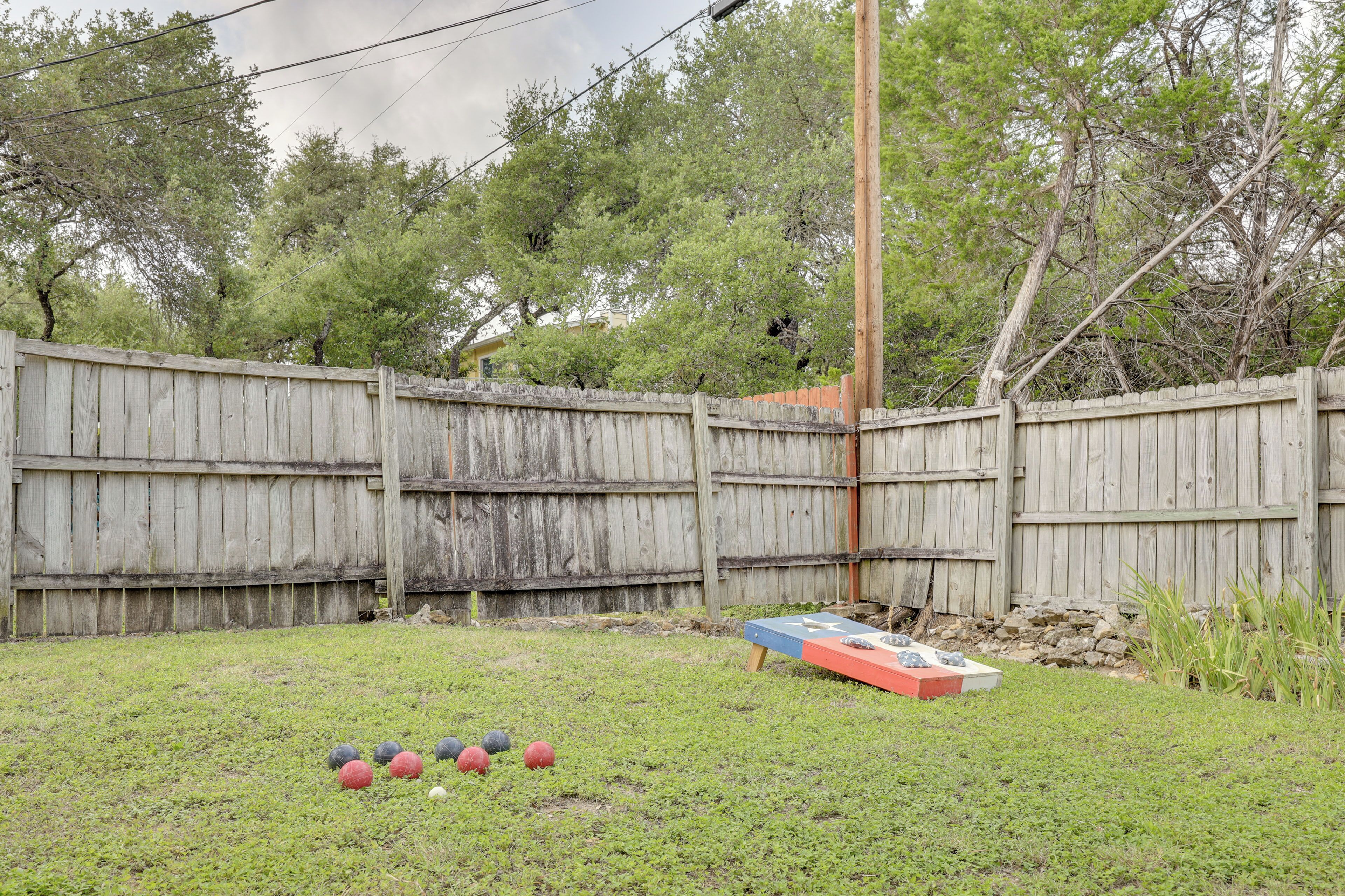 A backyard with a wooden fence, a small shed, and a lawn with several sports balls.