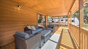 A covered porch with wicker furniture, a wooden ceiling, and a view of a trailer in the background.