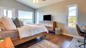 Um quarto com uma cama, televisão e vista para o oceano.