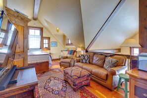 Ein gemütliches Schlafzimmer im Loft-Stil mit Hochbett, braunem Ledersofa, gemusterten Teppichen und einem Holztisch.