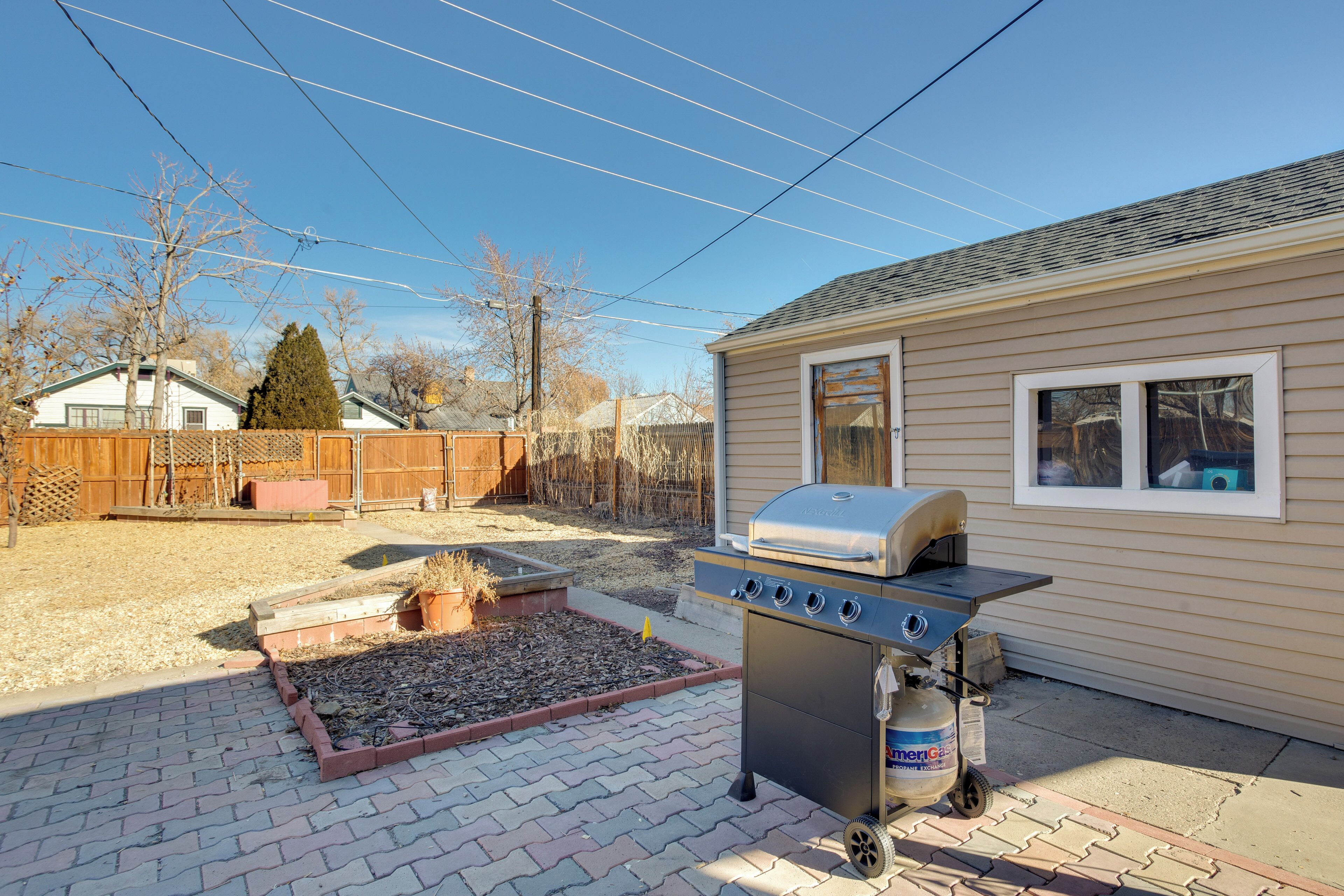 A backyard with a barbecue grill and a gas tank.
