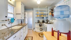Una cocina con encimeras de granito, armarios blancos, dispensador de agua y cafetera.