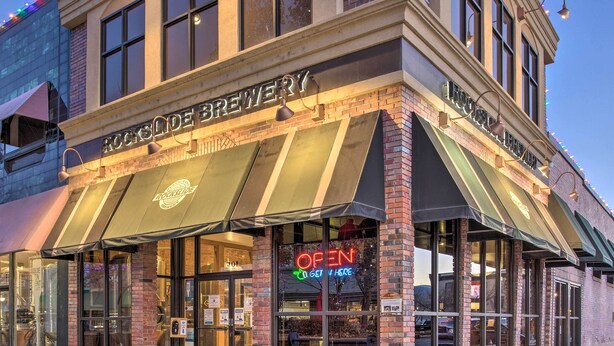 Un edificio de ladrillo con un cartel que dice "ROCKSIDE BREWERY" y un letrero de neón que indica "ABIERTO PARA ENTRAR AQUÍ".