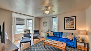 A living room with a blue sofa, two chairs, a coffee table, a ceiling fan, and a window with blinds. - Chic Downtown Home w/ Grill, Steps to Main Street! (Buena Vista)