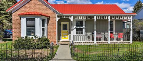 A two-story house with a red roof, a front porch, and a small front yard.