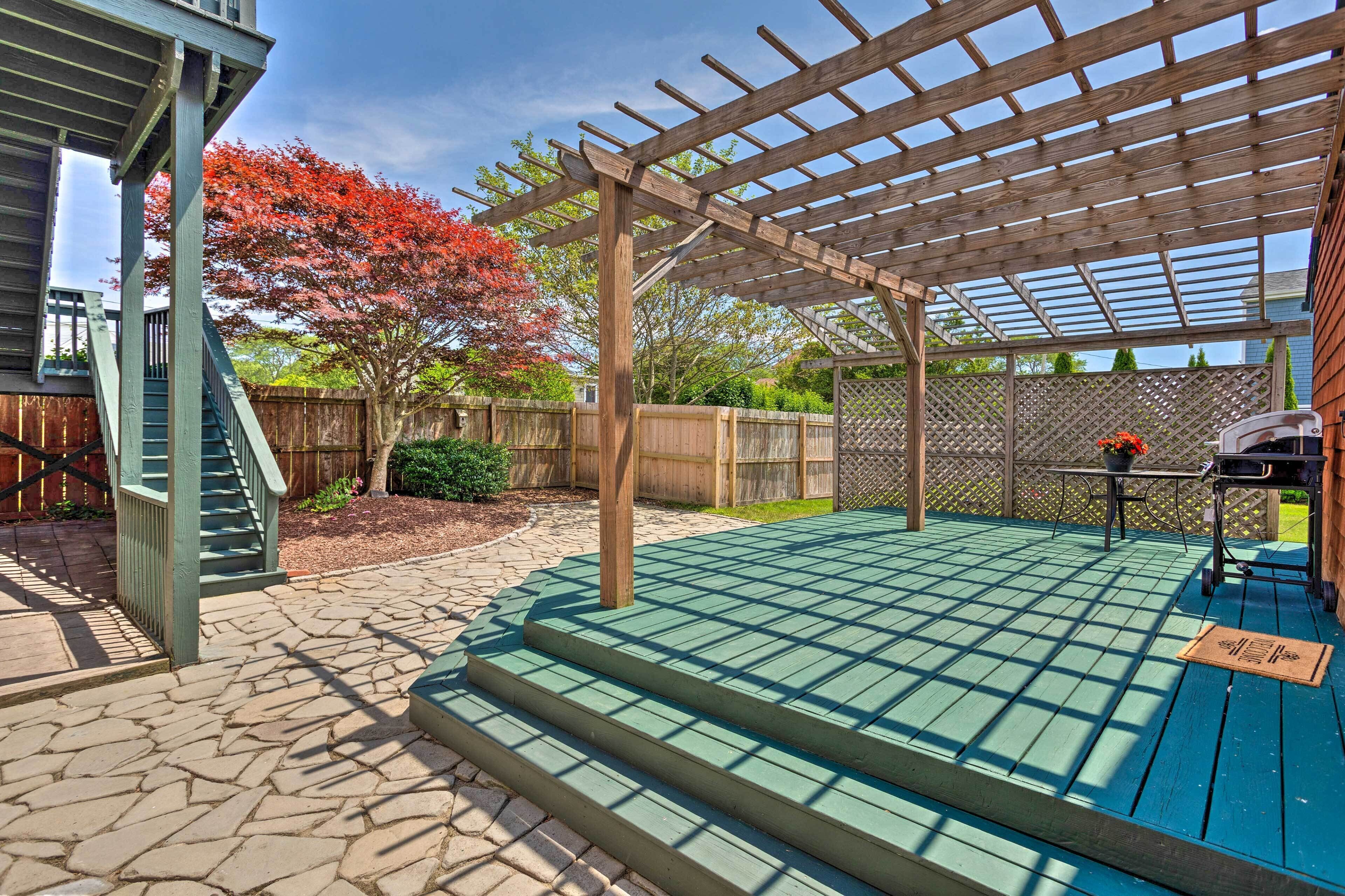 Un porche cubierto con pérgola, escalones de piedra y una terraza de madera.