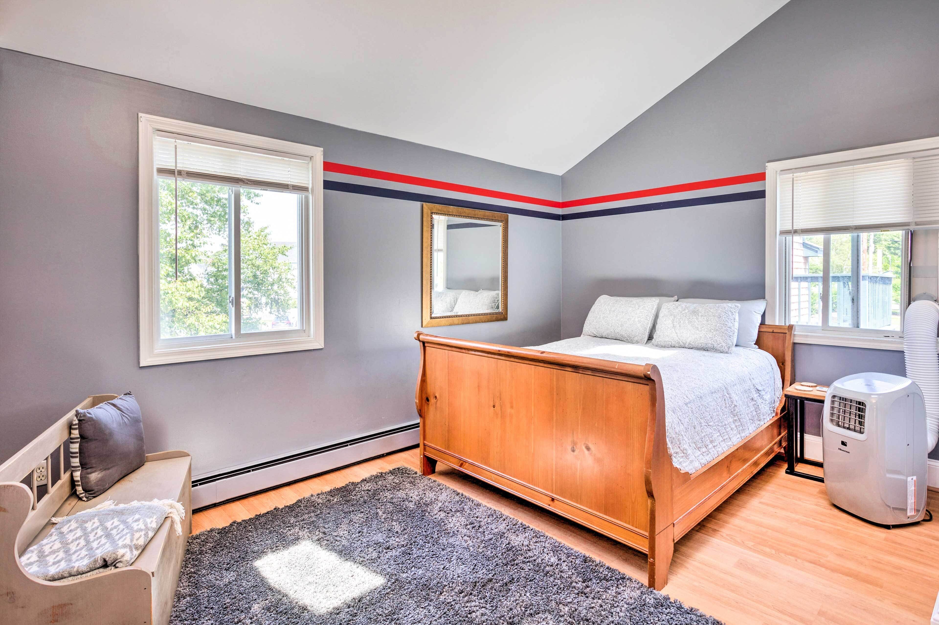 A bedroom with a wooden bed, a bedside table, a heater, and a window with blinds.
