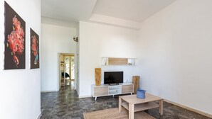 Uma sala de estar moderna com televisão de tela plana, mesa de centro de madeira e um sofá.