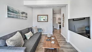 Un salon moderne avec un canapé gris, une table basse en bois et un grand tableau accroché au mur.