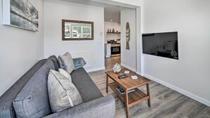Un salon moderne avec un canapé gris, une table basse en bois et un téléviseur fixé au mur.