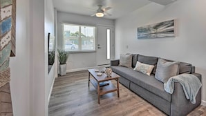 Un salon moderne avec un canapé gris, une table basse en bois et un ventilateur de plafond.