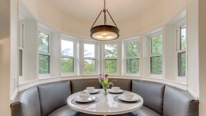 Un coin repas avec une table ronde, quatre chaises et un vase rempli de fleurs.