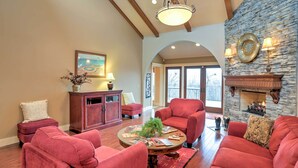 A spacious living room with red sofas, a wooden coffee table, and a stone fireplace. - Beautiful Central Fayetteville Townhome w/ Views! (Fayetteville)