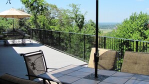An outdoor patio with a table and chairs, a large umbrella, and a view of the surrounding landscape. - Beautiful Central Fayetteville Townhome w/ Views! (Fayetteville)