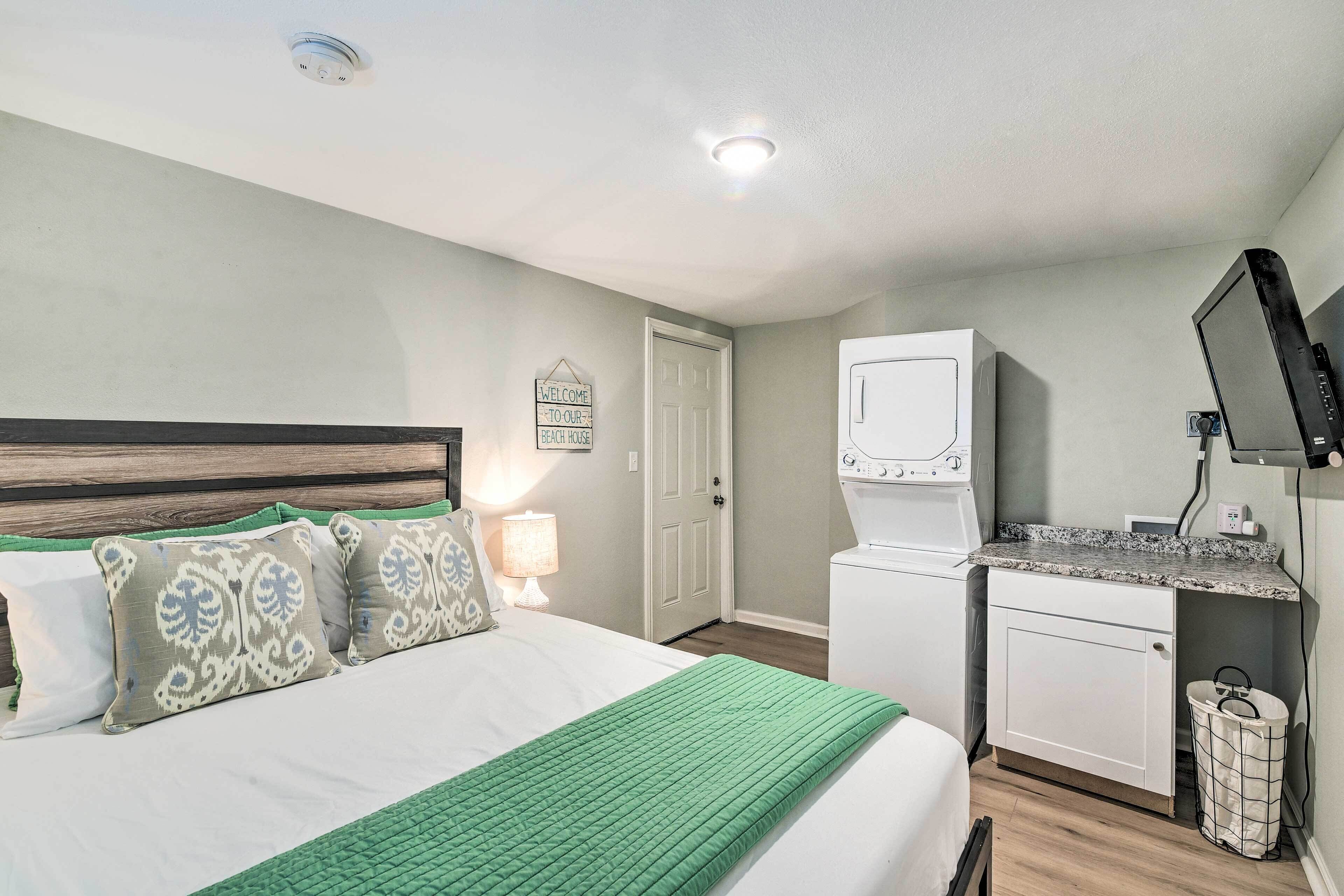 Une chambre à coucher avec un lit, une table de chevet, un bureau et un lave-linge.