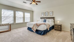 Ein Schlafzimmer mit Bett, Nachttisch, Kommode und Deckenventilator.