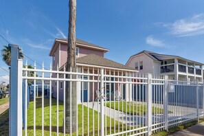 Um imóvel residencial com quintal cercado, casa de dois andares e varanda.