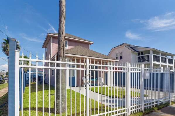 Una propiedad residencial con patio cercado, una casa de dos pisos y un garaje visible.