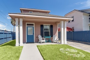 A single-story house with a front porch, a blue door, and two white chairs.