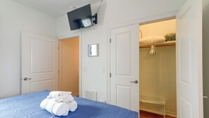 Ein Schlafzimmer mit einem Bett, einem an der Wand befestigten Fernseher und einem Schrank mit Sitzbank.