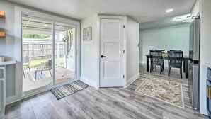 A modern kitchen with a dining area, a sliding glass door leading to a patio, and a refrigerator.