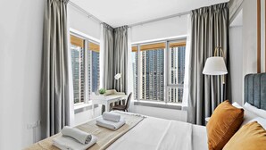 A hotel room with a large bed, a desk, and a view of tall buildings. - Silkhaus 29 Boulevard, Downtown Dubai (Dubai)